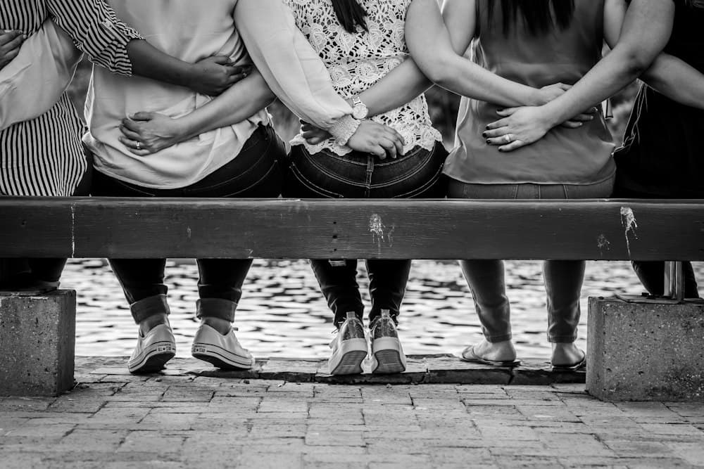 Three women sitting on a bench with their arms around each other