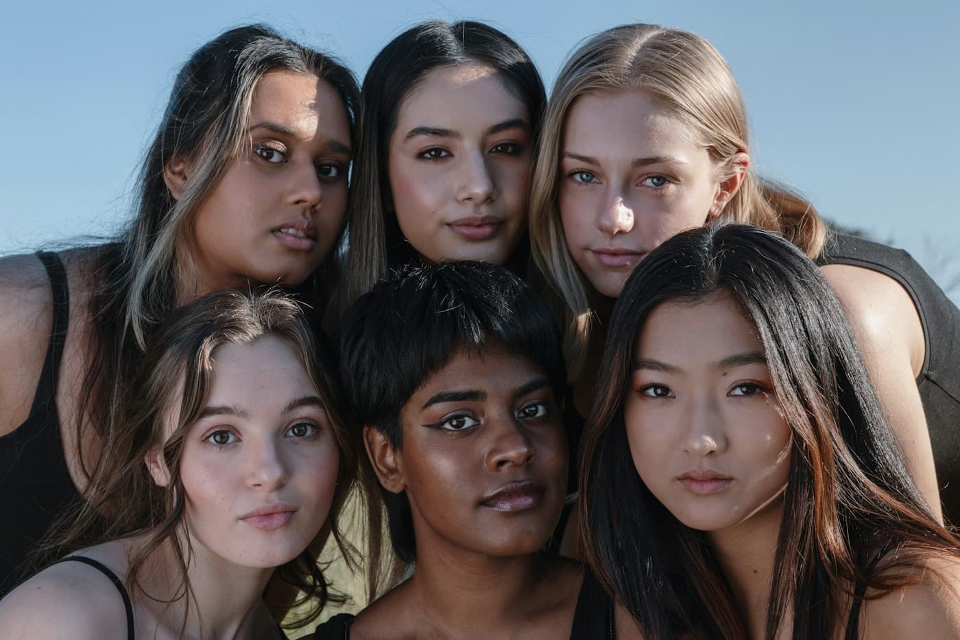 A close group of young women of different backgrounds looking into the camera