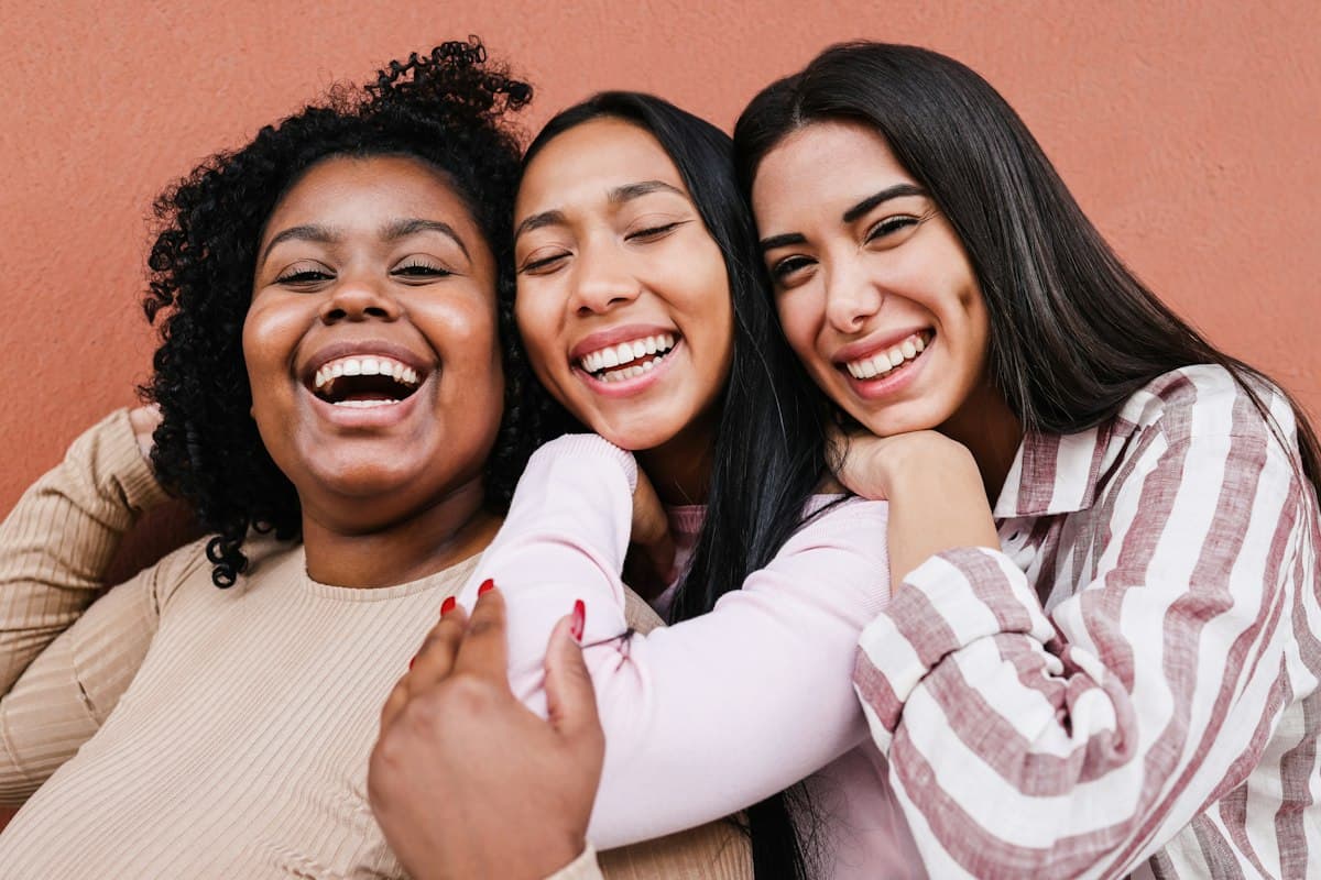 Three women laughing together, arms around each other